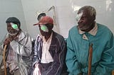 Three male participants in cataract surgery in Kenya sitting beside each other