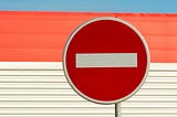 Red and white round sign against a blue, red, and white wall
