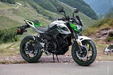 The Kawasaki Z e-1 electric sport motorcycle with mountain in the background.