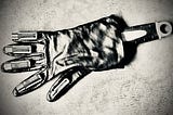 A robotic hand, simulated with a spanner inside a glove, with batteries on each of the fingers and thumb, in black and white. Arty image