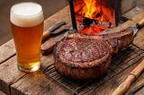 A rugged, rustic wooden table with a massive, perfectly cooked buffalo steak fresh off an open fire, sitting next to a foaming, homemade pint of beer and hand-carved tools.