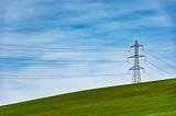 An electrical tower on a grass field.