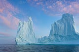 small red sailboat in front of iceberg