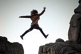 Photo of woman jumping a chasm. By Sammie Chaffin on Unsplash