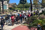 Photo of a large crowd of people holding picket signs and megaphones.