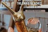 golden snail with a glass orb for a body held in a hand