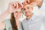 A man and a woman both holding the keys to a new house.
