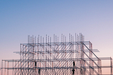 [Photo] Silhouette of four people on a steel-frame building construction.