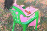 A person sits on a green chair in nature, head to the sky, feeling.