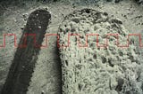 Black and white photo of a bread knife and a piece of cut bread with a red square-tooth wave running across the image