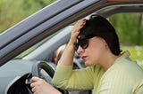 Woman in driver’s seat of a stopped car, looking distressed