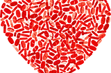 A red heart shape created using pills of different shapes and sizes.