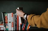 a picture of someone picking up a book from a row of books