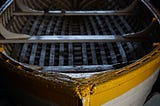 A yellow rowboat, close up. No oars.