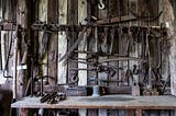An image of rustic tools organised on a wall with a work bench underneath