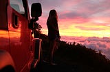 Girl looking over a cloudy sunset view.