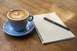 blue cup of coffee with a notepad on a table — ready to start your day