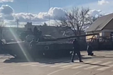 man kneeling in front of tank