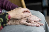 A close up of a woman holding an elderly lady’s hand.