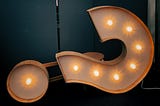 a large lighted question mark tilted on its right