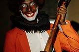 person dressed as terrifying clown, approaching camera brandishing sledgehammer