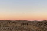 Sunset landscape of barren Nevada desert with full moon.
