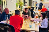 People sitting around two tables playing board and card games