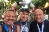 Three smiling runners at the finish of a half marathon event