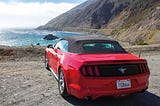 a red mustang overlooking a cliff.