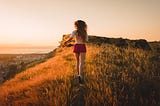 Woman with long hair running through a field.