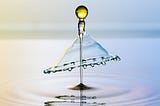 Colorful droplet rising from pool of water