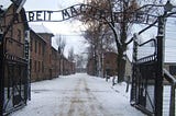 Image of the entrance to the Auschwitz Concentration Camp, snow blankets the ground
