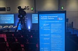 Empty stage and seating area at a conference. The stage is rather grandly named the ‘Digitally Empowered Patients Theatre’.