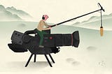 Producer sitting on a gigantic video camera to film