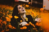 A lady laughs joyfully amongst flowers