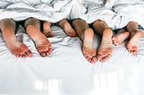 Picture with a blanket over a family while her foot sticks out.