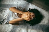 Woman lying down, hands covering face. Image credit: anthony-tran-i-ePv9Dxg7U-unsplash