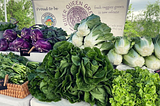 Farmers’ Market table full of bok choy, salad greens, purple cabbage, and herbs from River Queen Greens — a Certified Naturally Grown Vegetable Farm in NOLA.