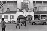 Native Americans play basketball at Alcatraz, in front of a sign that reads Indians Welcome, Indian Land.