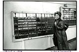 Picture of author Toni Morrison from April 14, 1978. Toni is standing in front of a departure schedule in a train station.