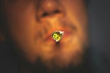 A joint with the weed pronounced in the light (in a blurred guy’s mouth)