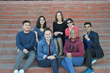 Seven people sitting on steps and smiling at the camera