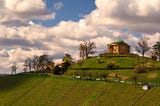 A grand sandstone Church set in a rural green hillside with vaguely surreal clouds in Rotenberg, Stuttgart, Germany