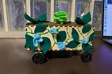 Box with a green flower and felt leaves on wheels