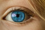 A close-up  shot of a beautiful blue eye reflecting three crosses across the iris
