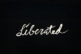 Cursive text — Liberated — on a black background