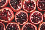 Lines of fresh pomegranates sliced in half with arils facing up