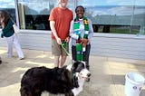 Williams College. James and his english shepherd dog being blessed by the chaplain in front of Pareski Hall. 2024. St. Francis Day