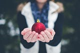 Engaged girl holding a red glittery christmas bauble in the snow