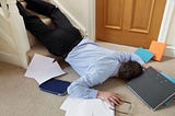 Businessman lying on floor at home surrounded by papers